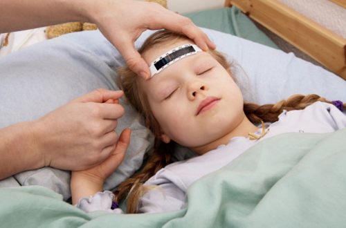 A young girl having her temperature taken with a forehead thermometer strip