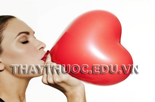 Girl blowing up a red heart shaped balloon